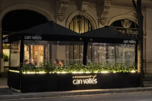 Cerramiento de terraza de restaurante con jardineras iluminadas y laterales transparentes en invierno